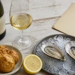 Bourgogne blanc aligoté sur table : verre tulipe, huîtres et gougères